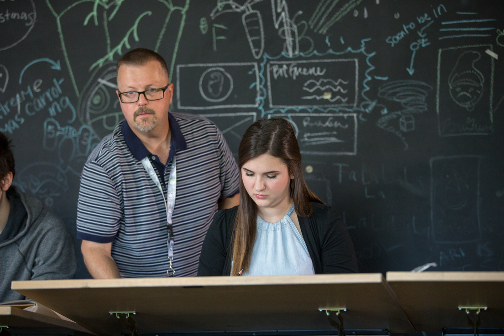Instructor teaching a student in front of a blackboard
