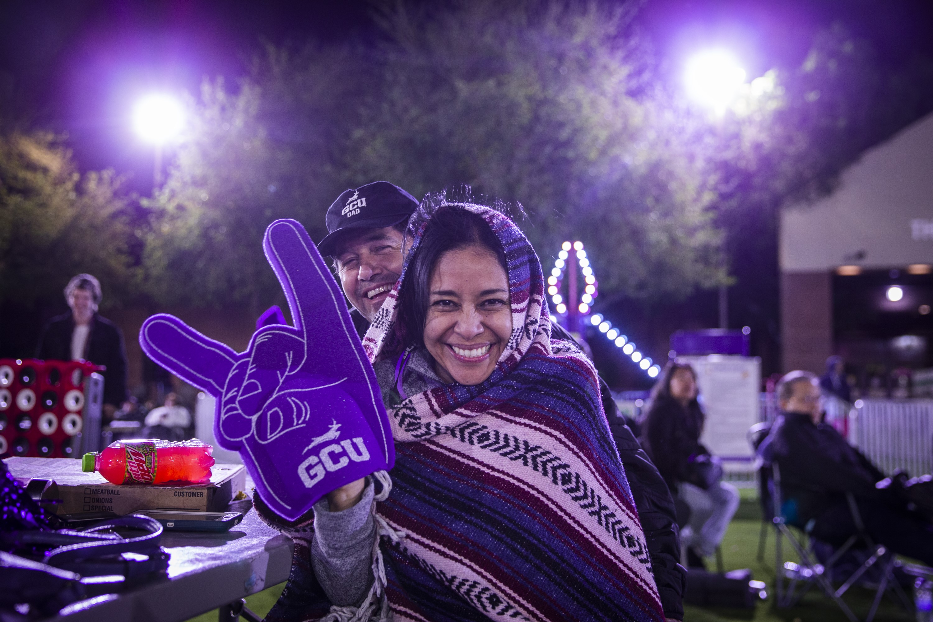 GCU student and her father hugging while holding up foam hand
