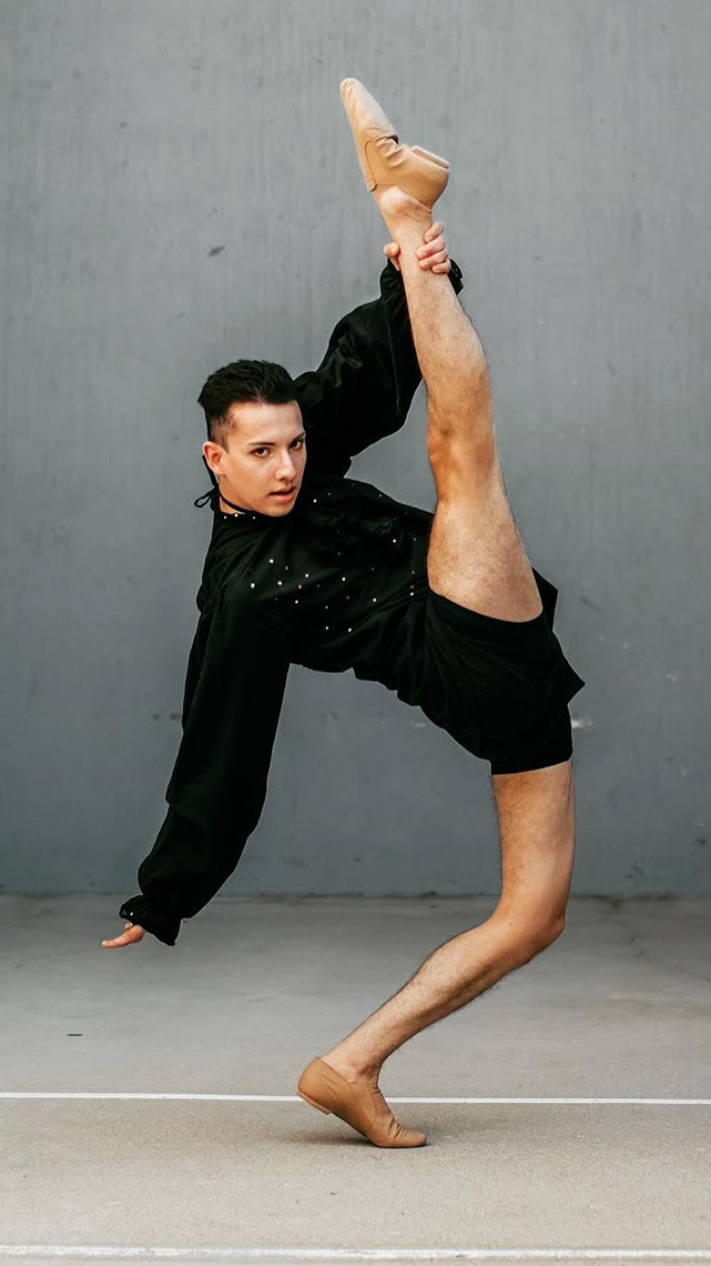 Jonathan Gerardo in a blank long sleeved top and dance shorts strikes a cortortionist split pose