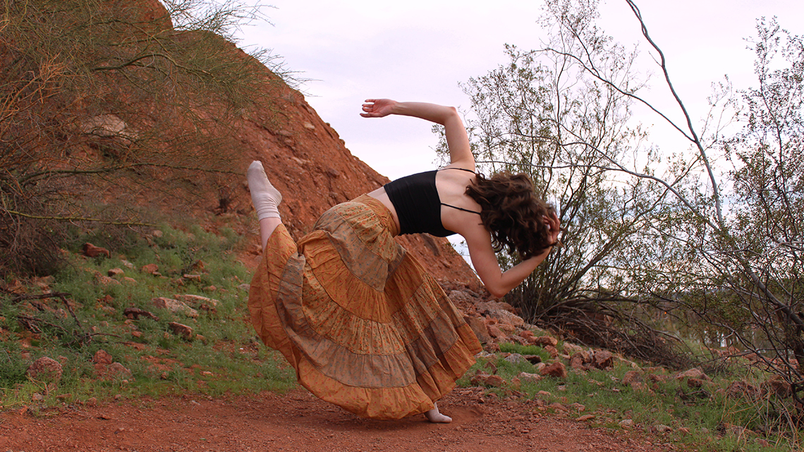 abstract dance movement by dancer in black top and brown skirt in the desert
