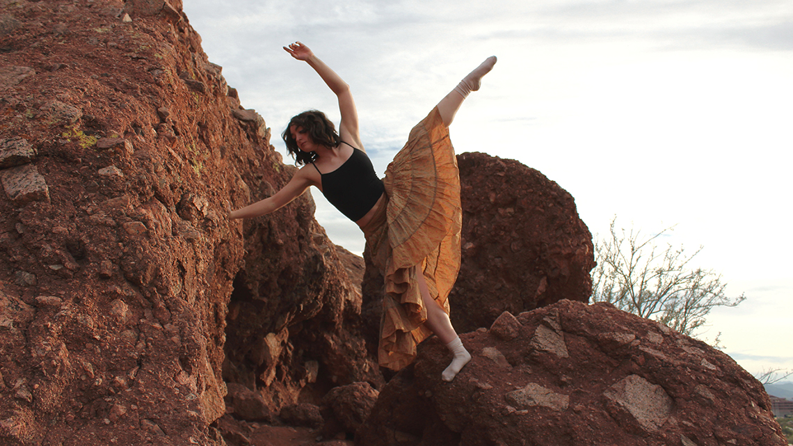 Kick leg split dance movement supported by desert boulders