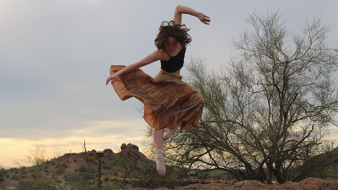 Sammi does a jump with pointe toe in desert landscape
